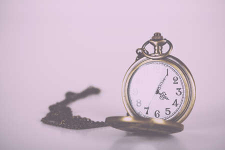 Pocket watch against a light coloured background Vintage Retro Filter.