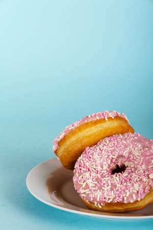 Iced pink donut on a light coloured blue backgroundの写真素材