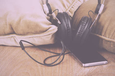 Headphones resting on cushions on a wooden surface Vintage Retro Filter.の写真素材