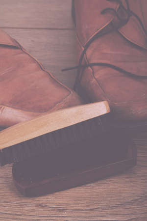 Shoes and cleaning equipment on a rustic wooden floor Vintage Retro Filter.の写真素材