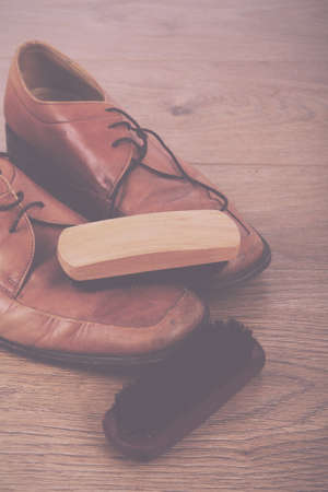 Shoes and cleaning equipment on a rustic wooden floor Vintage Retro Filter.の写真素材