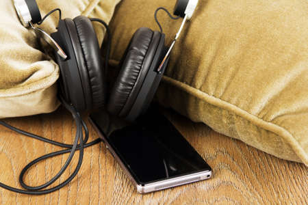 Headphones resting on cushions on a wooden surfaceの写真素材