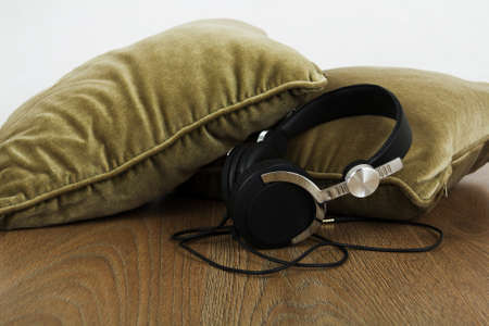 Headphones resting on cushions on a wooden surfaceの写真素材
