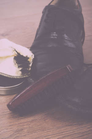 Shoes and cleaning equipment on a rustic wooden floor Vintage Retro Filter.の写真素材