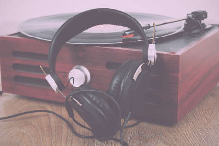 Black headphones on an old retro record player Vintage Retro Filter.の写真素材