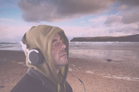 Man in hoodie listening to music on headphones Vintage Retro Filter.の写真素材