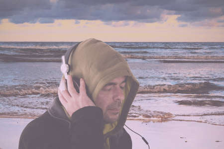 Man in hoodie listening to music on headphones Vintage Retro Filter.