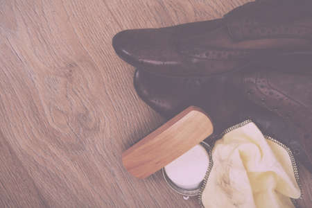Shoes and cleaning equipment on a rustic wooden floor Vintage Retro Filter.の写真素材