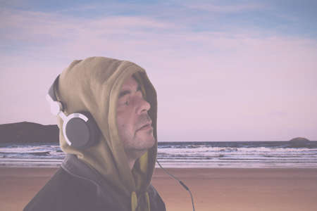 Man in hoodie listening to music on headphones Vintage Retro Filter.の写真素材