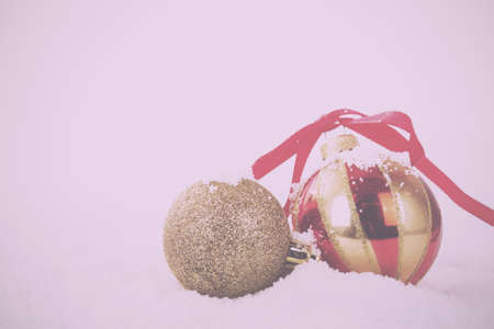 Gold Christmas decorations in white snow for a background Vintage Retro Filter.の写真素材