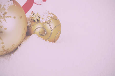 Gold Christmas decorations in white snow for a background Vintage Retro Filter.の写真素材
