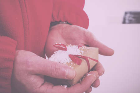 Open hands holding a present wrapped in a red ribbon Vintage Retro Filter.の写真素材