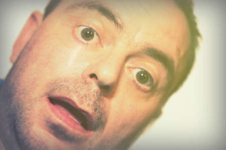 Man talking selfie while pulling funny face on white backgroundの写真素材