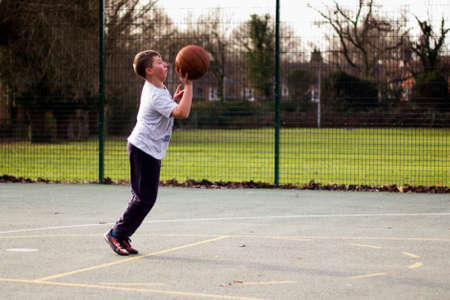 Child practicing playing basketball in a local parkの写真素材