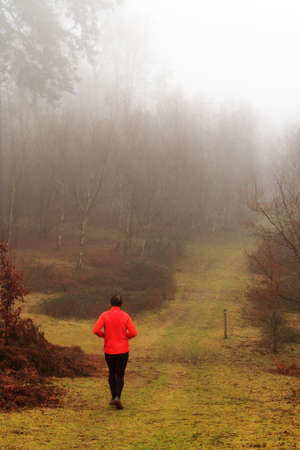 Man jogging in woodland on a foggy misty January morningの写真素材