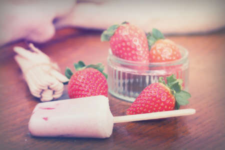 Homemade strawberry ice lolly on a rustic backgroundの写真素材
