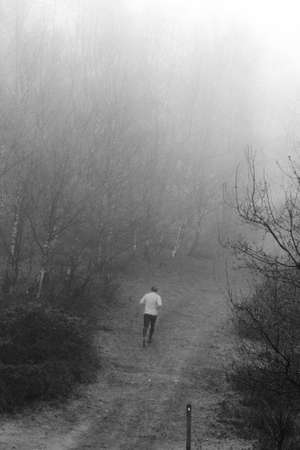 Man jogging in woodland on a foggy misty January morningの写真素材