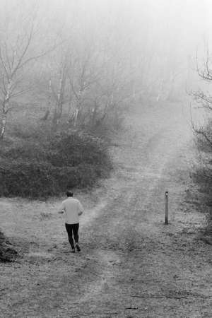 Man jogging in woodland on a foggy misty January morningの写真素材