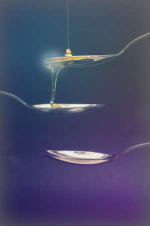 Honey pouring from a spoon against a dark background