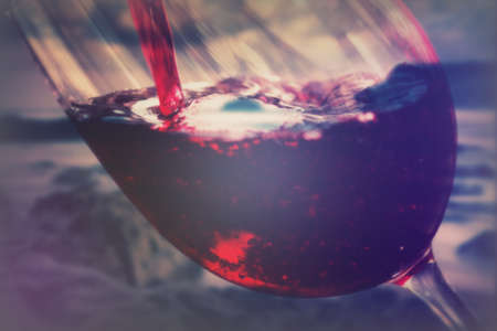 Glass of full bodied red wine being poured from bottleの写真素材