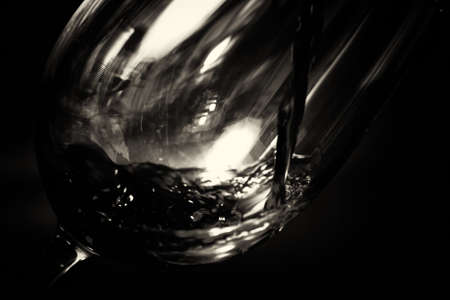 Glass of full bodied red wine being poured from bottleの写真素材