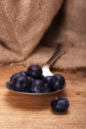 Blueberries and silver spoon on a rustic backgroundの写真素材