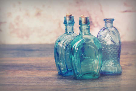 Selection of coloured glass bottles on a rustic backgroundの写真素材