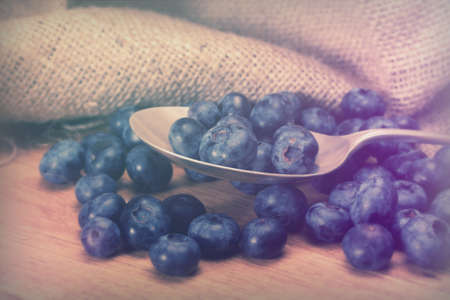 Blueberries and silver spoon on a rustic backgroundの写真素材