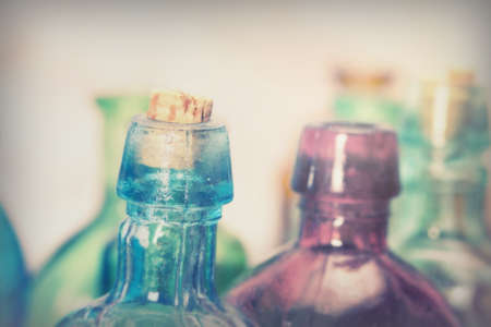 Selection of coloured glass bottles on a rustic backgroundの写真素材
