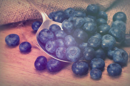 Blueberries and silver spoon on a rustic backgroundの写真素材