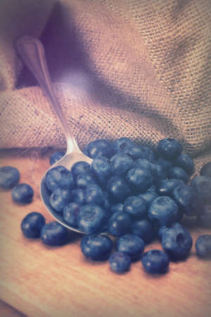 Blueberries and silver spoon on a rustic backgroundの写真素材