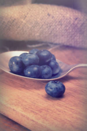 Blueberries and silver spoon on a rustic backgroundの写真素材