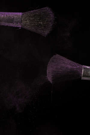 Make up brush with purple dust on a black backgroundの写真素材