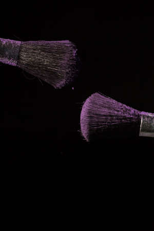 Make up brush with purple dust on a black backgroundの写真素材