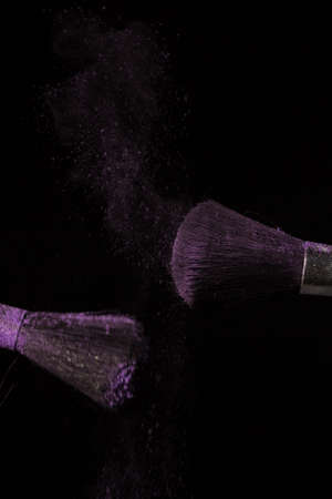Make up brush with purple dust on a black backgroundの写真素材