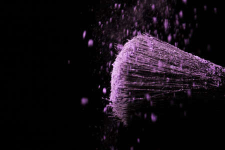 Make up brush with purple dust on a black backgroundの写真素材