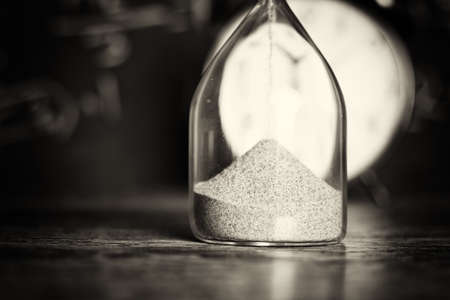 Hourglass against on wooden surface with a blackboard background