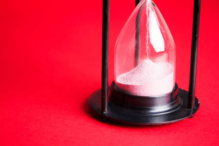 Large black hourglass against a bright red background