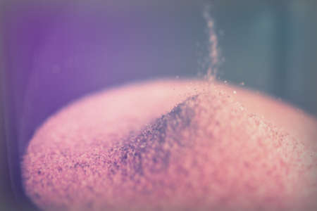 Large hourglass with pink sand against a black backgroundの写真素材