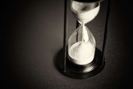 Large black hourglass against a bright red background