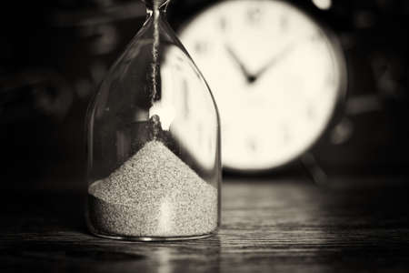 Hourglass against on wooden surface with a blackboard backgroundの写真素材