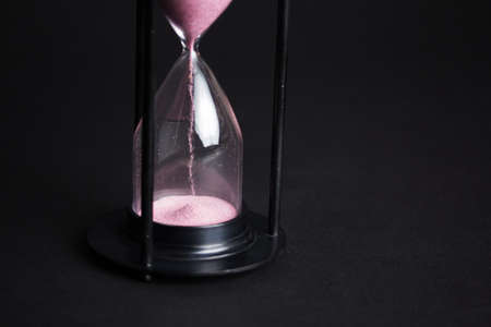 Large hourglass with pink sand against a black backgroundの写真素材