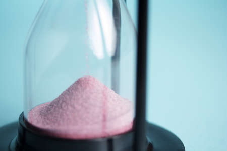 Large black hourglass against a light blue backgroundの写真素材