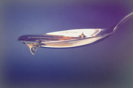 Honey pouring from a spoon against a dark backgroundの写真素材