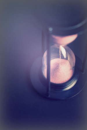Large hourglass with pink sand against a black background