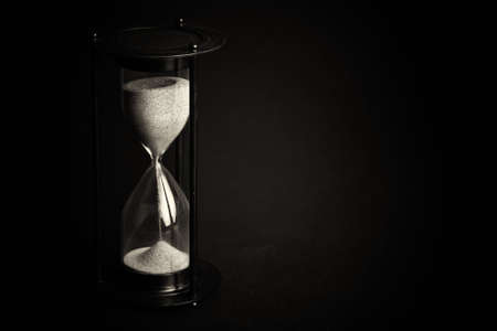 Large hourglass with pink sand against a black backgroundの写真素材