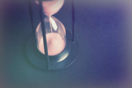 Large hourglass with pink sand against a black background
