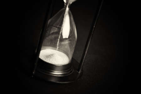 Large hourglass with pink sand against a black backgroundの写真素材