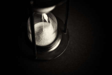 Large hourglass with pink sand against a black background