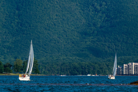 Two sail boats at the lake with the mountain in the backgroundの写真素材